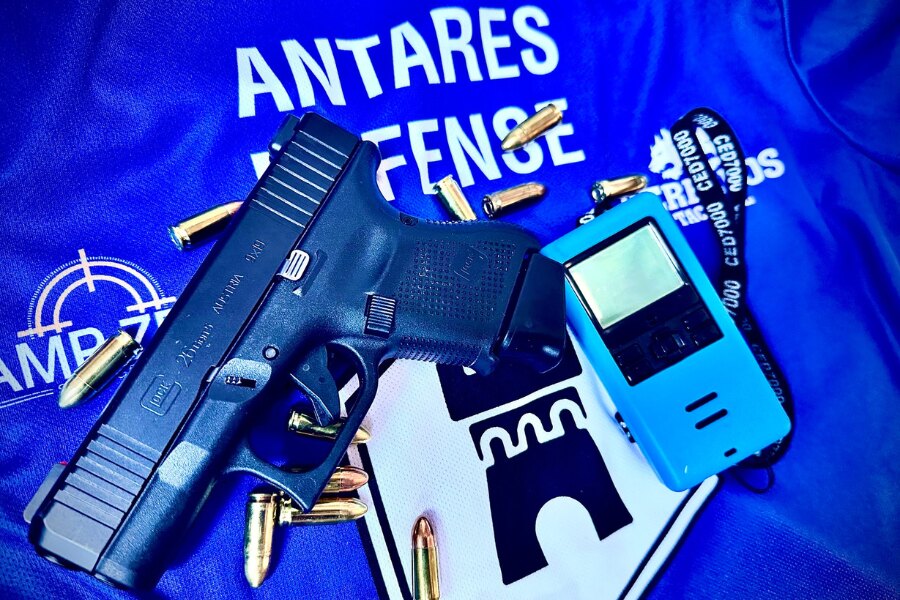 Tričko Antares Defense s logom, pištole Glock, náboje a merač času. Zdroj: Facebook Antares Defense.